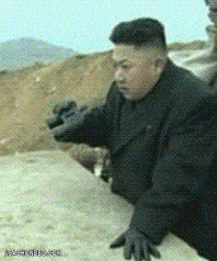 a man in a black suit and gloves is standing on a dirt road ..