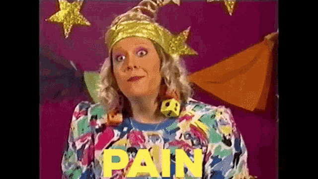 a woman in a colorful sweater is standing in front of a sign that says pain .