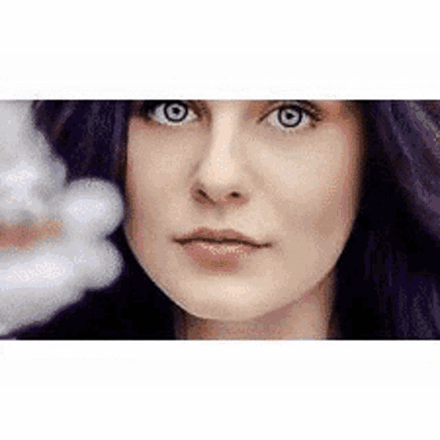 a close up of a woman 's face with purple hair looking at the camera .