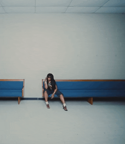 a woman sits on a blue bench in a waiting room