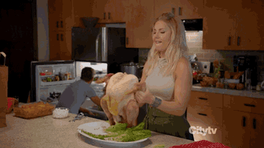 a woman is holding a chicken in a kitchen with the word citytv on the counter