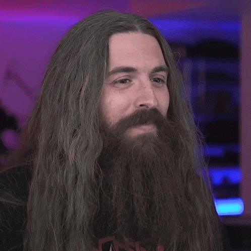 a man with long hair and a beard has the word wow on his shirt
