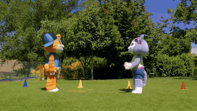 two stuffed animals are standing next to each other in a park