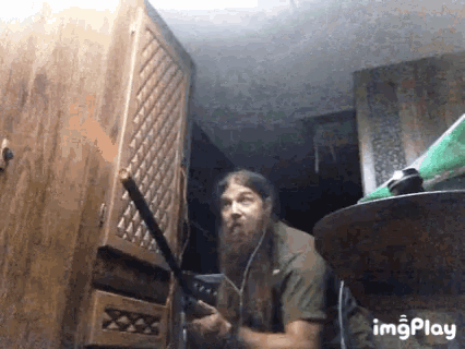 a man with a beard is playing a guitar in a room with the words imgplay below him .