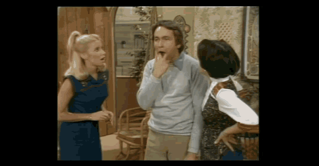 a man with his mouth open and two women standing around him