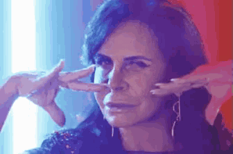 a woman is covering her ears with her hands and making a face .