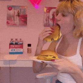 a woman eating a hamburger in front of a smirnoff ice box