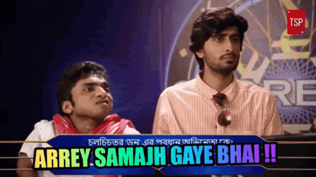 two men are sitting in front of a sign that says arrey samajh gaya bhai