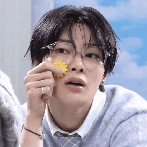 a close up of a person wearing glasses and holding a yellow object