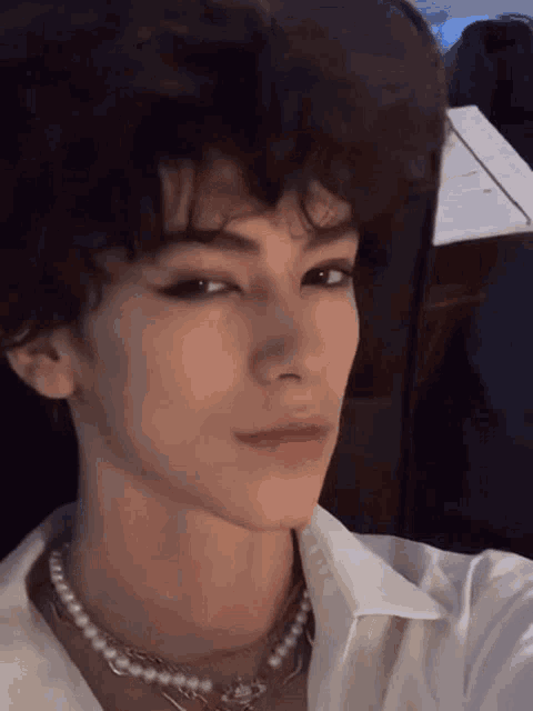 a close up of a person 's face wearing a pearl necklace and taking a selfie .