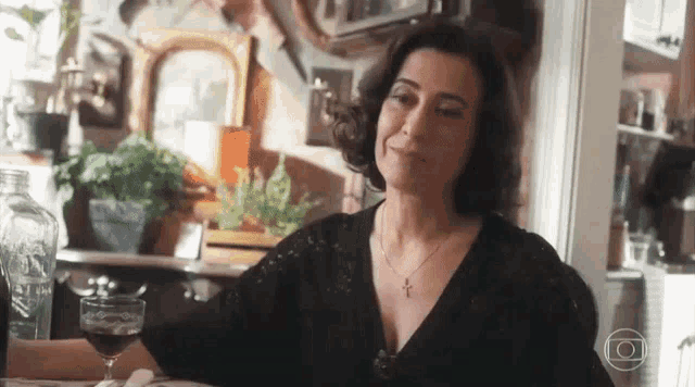 a woman is sitting at a table with a glass of wine in front of her