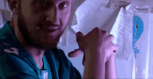 a man with a beard wearing a scrub top that says ' n ' on it