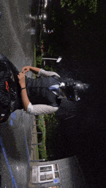 a man in a suit and tie is standing in the rain with a helmet on