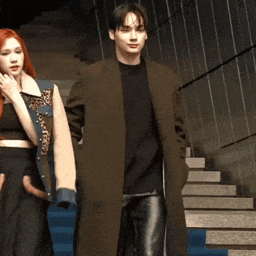 a man in a brown coat is standing next to a woman with red hair
