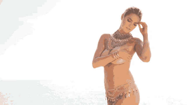 a naked woman wearing a necklace and bracelets covers her chest
