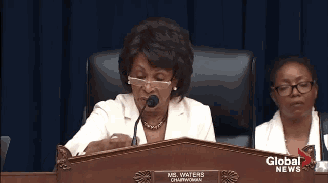 a woman sitting at a podium with the name ms. waters written on it