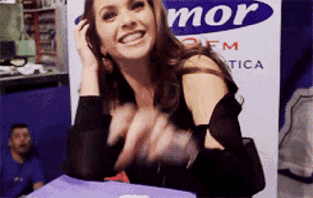 a woman smiles in front of a sign that says mor fm