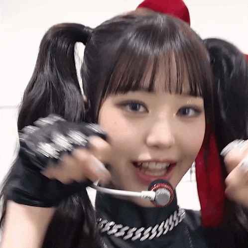 a close up of a girl with pigtails and a microphone in her mouth