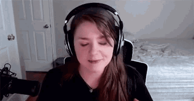 a woman wearing headphones is sitting in front of a microphone and smiling .