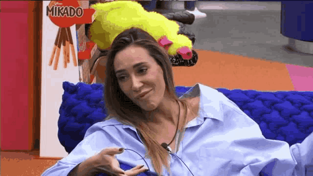 a woman is sitting on a blue couch in front of a mikado sign