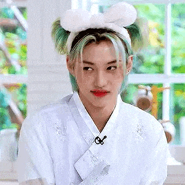 a young man with blue hair and a white headband is wearing a white shirt and a white headband .