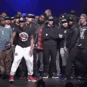 a group of men are standing on a stage and one of them is wearing a shirt that says " us "