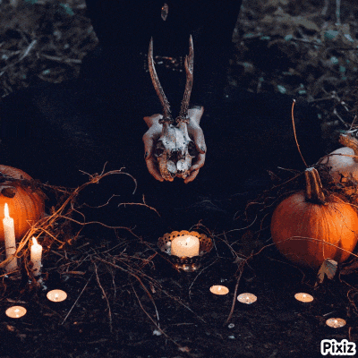 a person holding a deer skull in their hands next to a pumpkin and candles