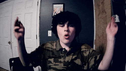 a boy wearing headphones and a camouflage shirt stands in front of a door