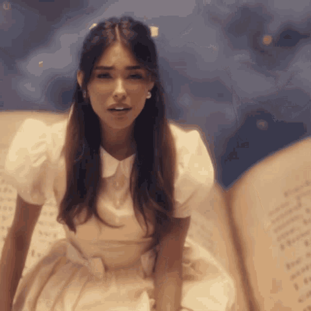 a woman in a white dress sits on a book