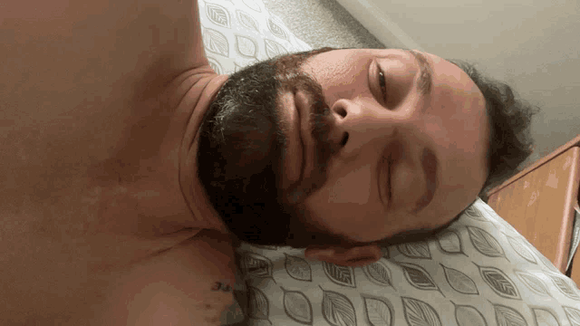 a man with a beard is sleeping on a bed