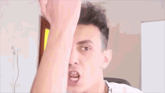 a young man wearing a white t-shirt with a black collar is making a funny face .