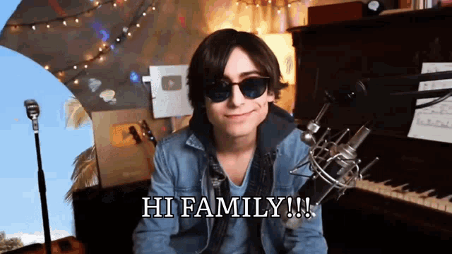 a man wearing sunglasses is sitting in front of a microphone and saying hi family