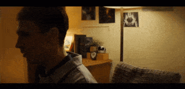 a man is standing in a room with a clock on the desk that says ' a ' on it