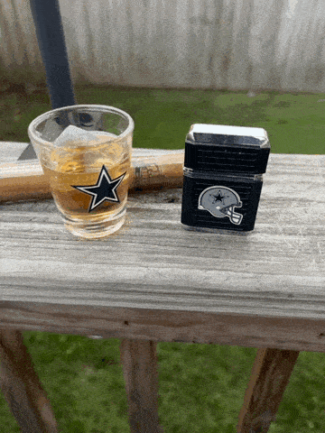 a shot glass with a cowboys star on it next to a lighter