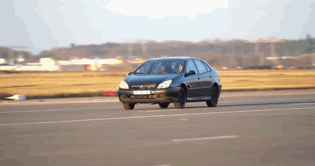 a black car with a license plate that says ' a ' on it drives down a road