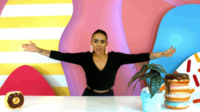 a woman is standing with her arms outstretched in front of a plant and donuts
