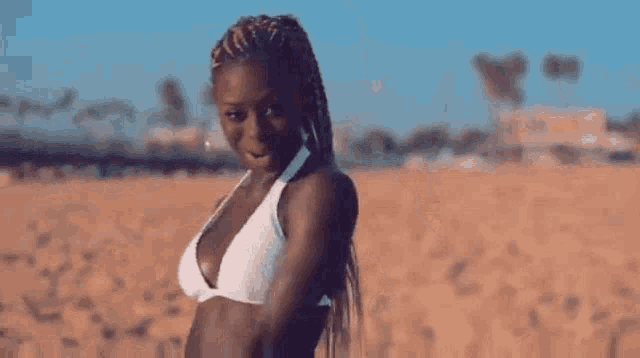 a woman in a white bikini is dancing on a beach .