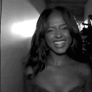 a black and white photo of a woman in a strapless dress smiling .