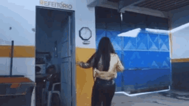 a woman walking into a room that says refeitorio on the wall