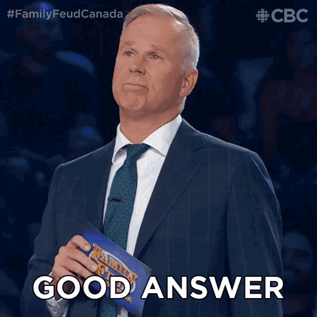 a man in a suit and tie holds a family feud card and says " good answer "