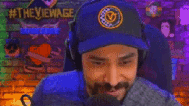 a man wearing headphones and a beanie is smiling in front of a brick wall with #theviewage written on it