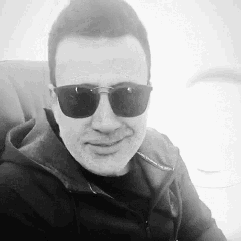 a black and white photo of a man wearing sunglasses and a black jacket