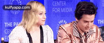 a man and a woman are sitting in front of a sign that says center for media .