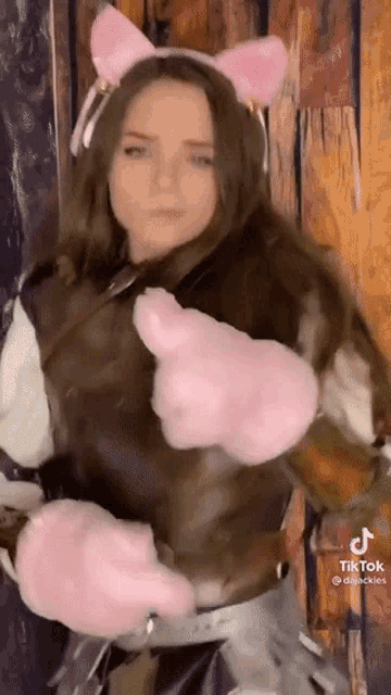 a woman in a cat costume with pink ears and gloves .