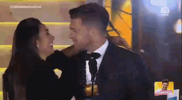 a man in a suit and tie kisses a woman on the neck