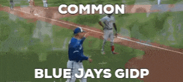 a man in a blue jays uniform is talking to a referee in a baseball game .