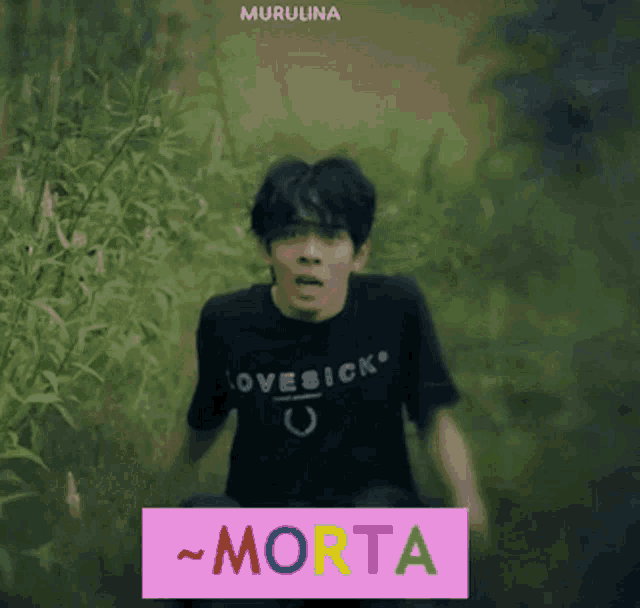 a man wearing a black shirt that says lovesick is running through a field