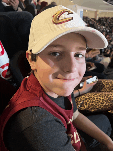 a young boy wearing a cleveland hat smiles
