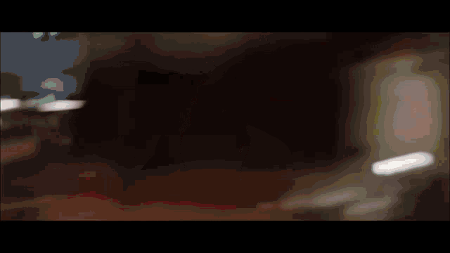 a blurry picture of a person in a white shirt standing in a dark room