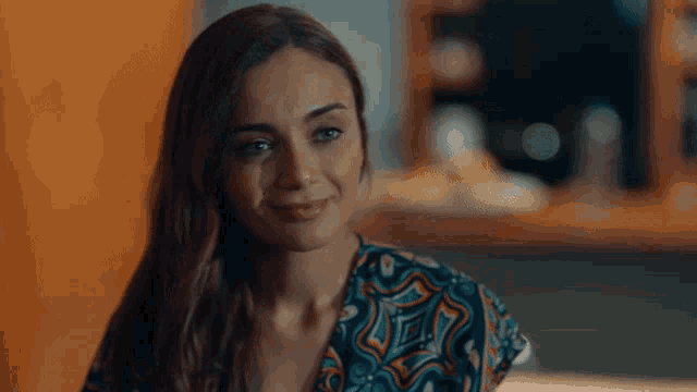 a woman wearing a colorful shirt is smiling and looking at the camera